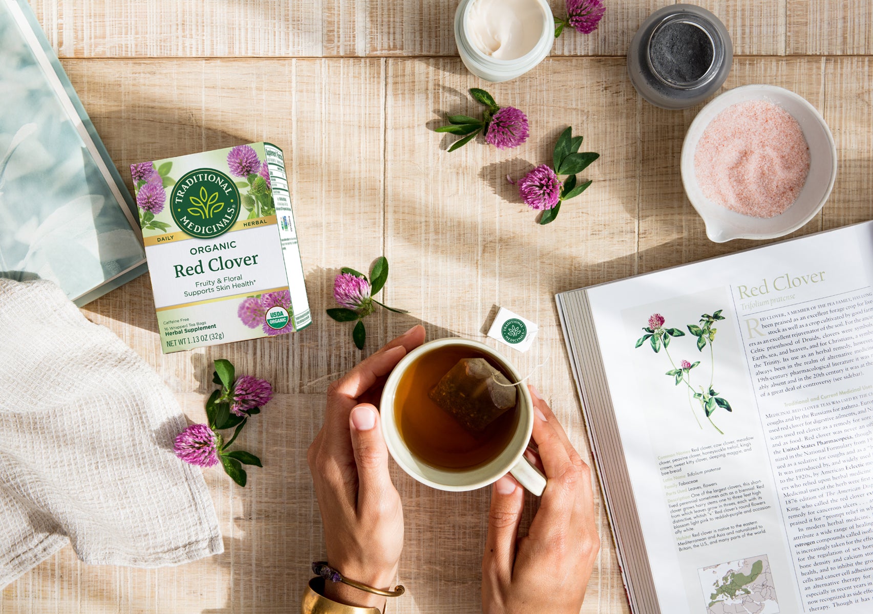 Person holding steeping cup of red clover tea 