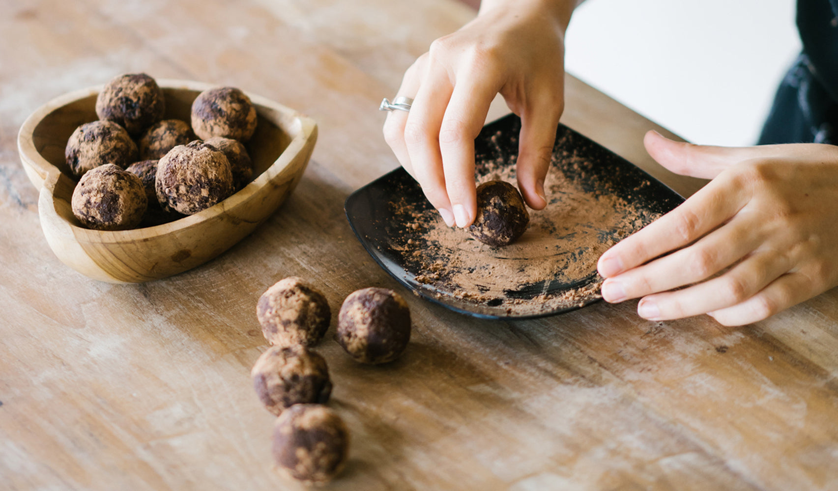 Woman dipping Lover's Truffles in powder /><h2>Damiana & Rosewater Lover’s Truffles</h2>
<p>Servings: 15-20 truffles<br />
Serving Size: Approx. 2 truffles<br />
Time: 20 mins prep a day ahead, 45 mins total</p>
<p><strong>Materials:</strong></p>
<ul>
<li>Mixing bowl</li>
<li>Parchment paper</li>
<li>2 trays for chocolate truffles</li>
<li>Spoon for mixing</li>
<li>Small cooking pot with cover</li>
<li>Small cookie scoop</li>
</ul>
<p><strong>Ingredients:</strong></p>
<ul>
<li>8 oz of Fair Trade Certified™ bittersweet chocolate</li>
<li>3/4 cup of full-fat coconut milk</li>
<li>1 small capful of rosewater</li>
<li>1 pinch of cardamom</li>
<li>3/4 cup of shredded coconut</li>
<li>1/3 cup cocoa powder unsweetened</li>
<li>1 pinch of salt</li>
<li>2 tablespoons of dried <a href=