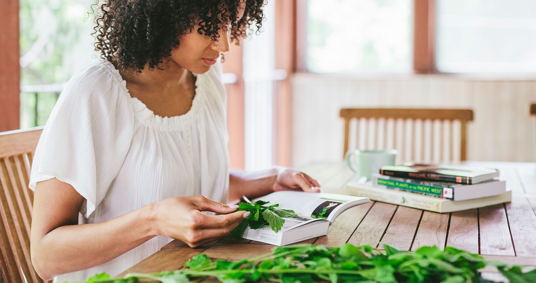 woman using reference book to identify herbs