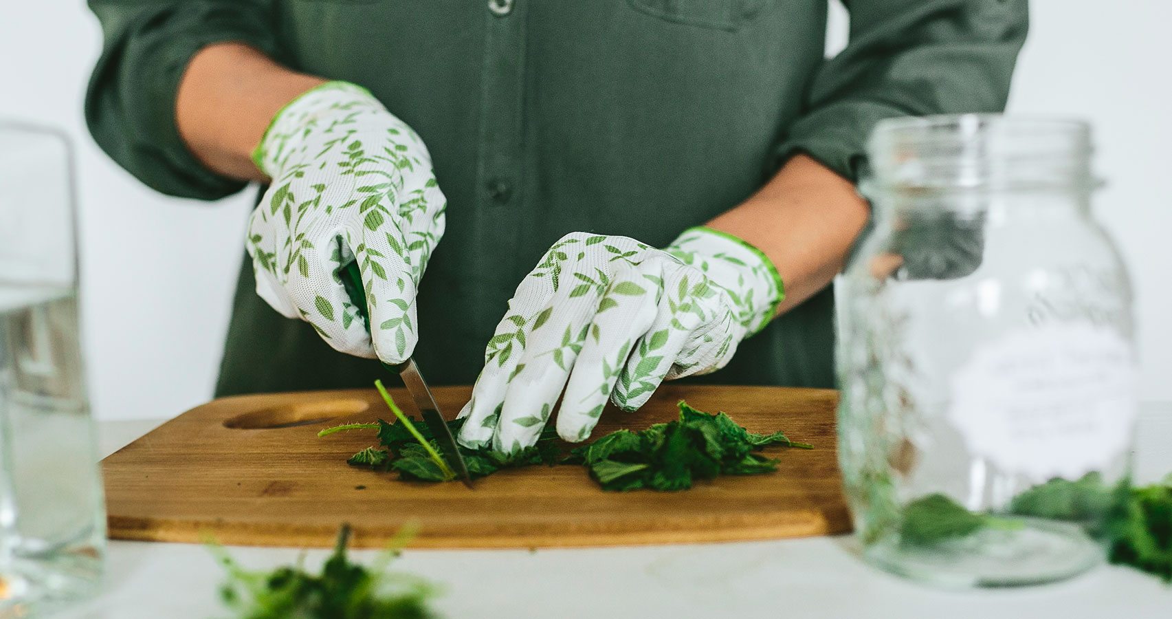 gloved hands cutting herbs