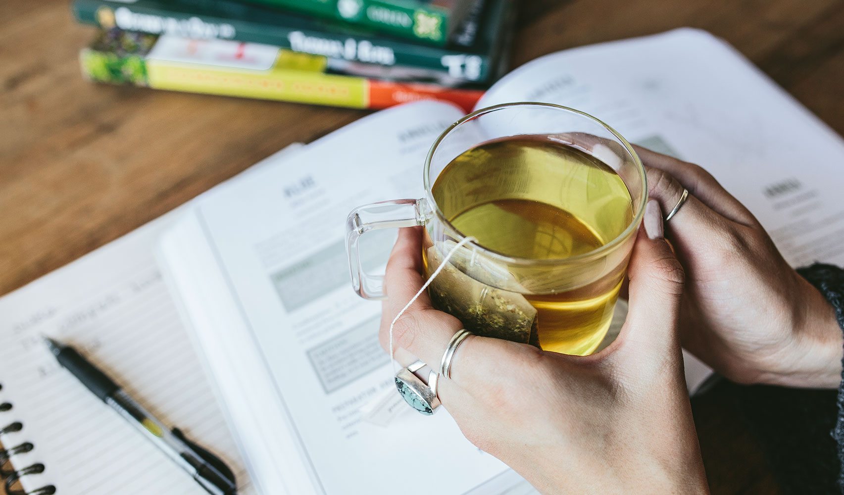 hands holding glass mug of tea